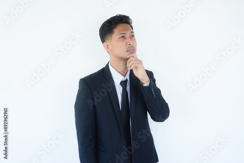 Asian businessman thinking about something while looking to upper right corner photo