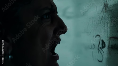 A detailed view of a persons horrified expression as they come face to face with a wall covered in ominous writing and drawings.