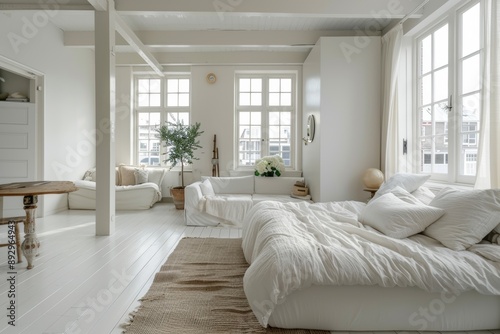 Interior of spacious bedroom with white walls, wooden floor and large windows.