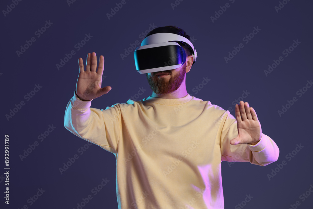 Man using virtual reality headset on dark purple background Man using virtual reality headset on dark purple background