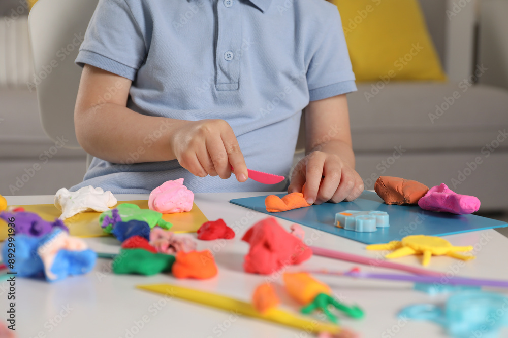 Little boy sculpting with play dough at table indoors, closeup Little boy sculpting with play dough at table indoors, closeup