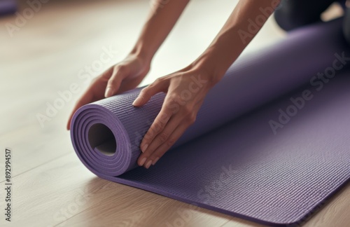 Woman's Hand Unrolling a Purple Yoga Mat on Wooden Floor in Modern Studio, Sport and Healthy Lifestyle Concept 