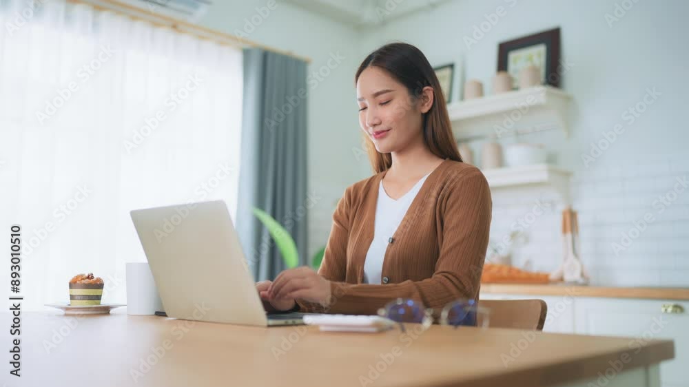 Beautiful young Asian woman working with laptop computer in home kitchen. Work at home Beautiful young Asian woman working with laptop computer in home kitchen. Work at home