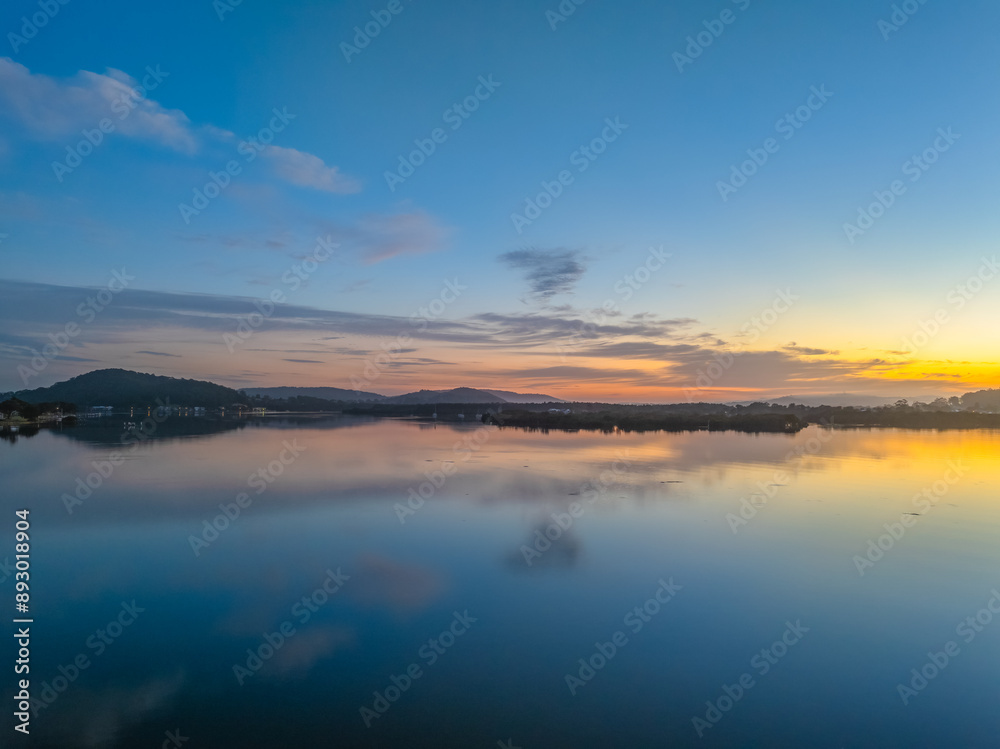 Sunrise along the waterfront with reflections on the bay water Sunrise along the waterfront with reflections on the bay water