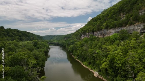 Approaching a bridge over the Kentucky River while flying through a canyon covered in trees and vegetation.