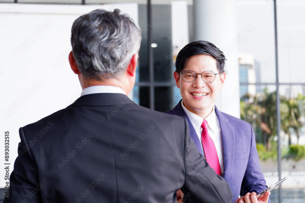Male businessman standing and smiling inside the office. Male businessman standing and smiling inside the office.
