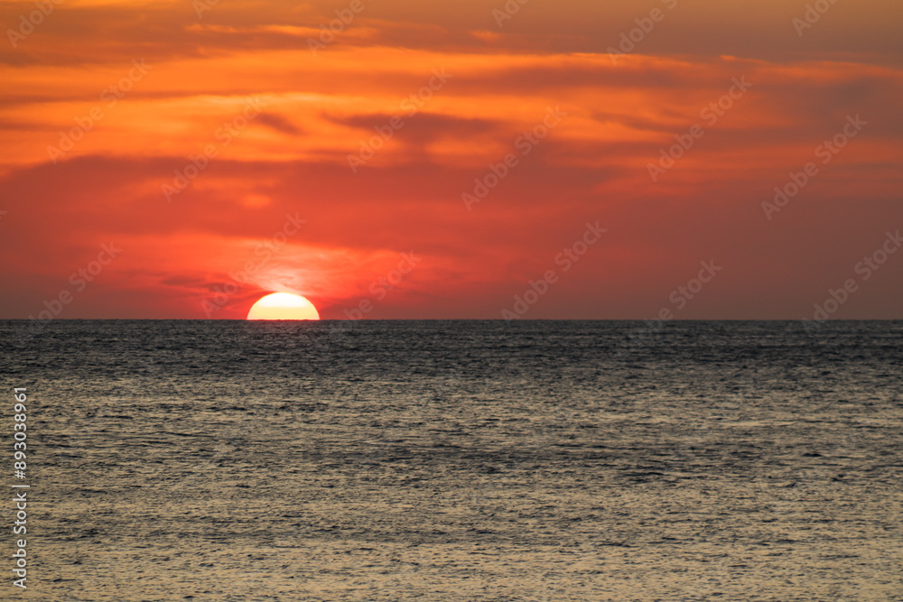 The vast ocean with the setting sun above the horizon line The vast ocean with the setting sun above the horizon line