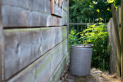 tin dustbin outside an old wooden cottage in a village