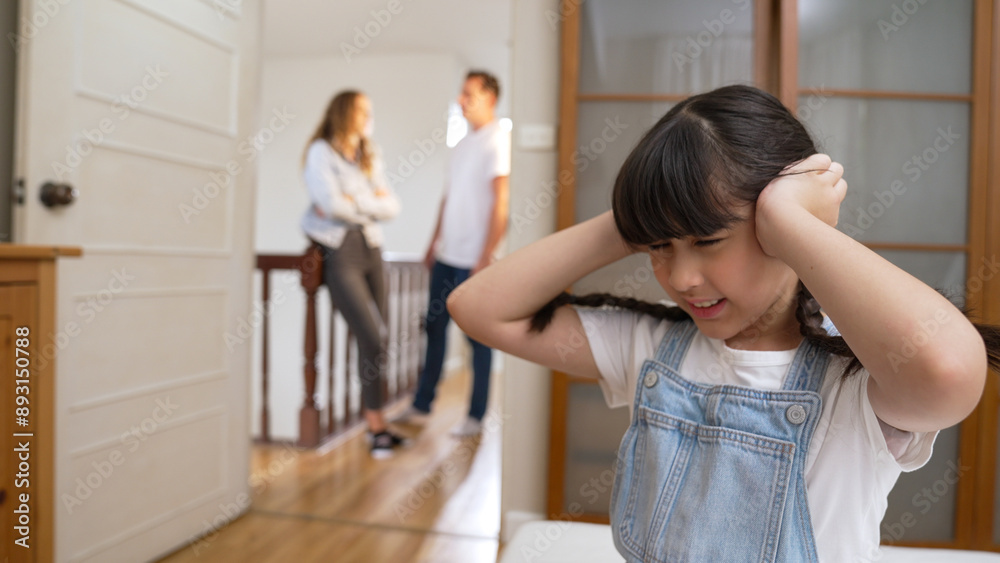 Stressed and unhappy young girl huddle in corner, cover her ears blocking sound of her parent arguing in background. Domestic violence at home and traumatic childhood develop to depression. Synchronos Stressed and unhappy young girl huddle in corner, cover her ears blocking sound of her parent arguing in background. Domestic violence at home and traumatic childhood develop to depression. Synchronos