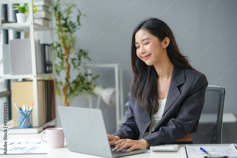 Young businesswoman happily works from her home office, focused on her laptop and paperwork with a cup of coffee. She types away, showcasing a modern work environment Young businesswoman happily works from her home office, focused on her laptop and paperwork with a cup of coffee. She types away, showcasing a modern work environment