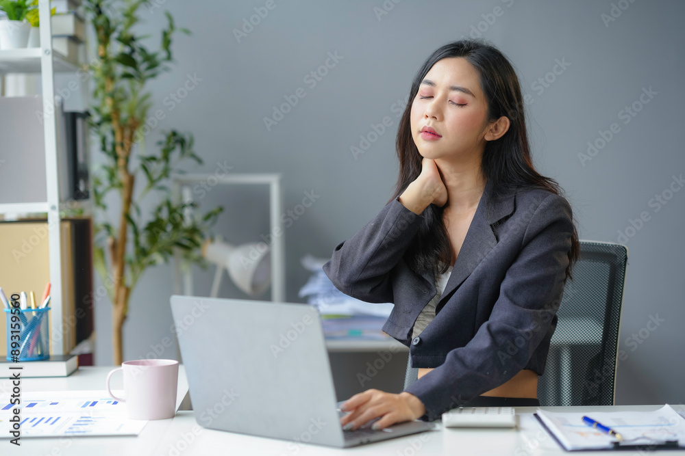Stressed businesswoman massages neck while working on laptop in office, showing struggle of balancing career with health issues Stressed businesswoman massages neck while working on laptop in office, showing struggle of balancing career with health issues