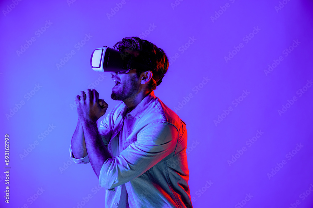 Caucasian man singing a song in virtual world at neon background by using VR goggles or technology innovation. Teenager standing and moving gesture while wear casual cloth and headsets. Deviation. Caucasian man singing a song in virtual world at neon background by using VR goggles or technology innovation. Teenager standing and moving gesture while wear casual cloth and headsets. Deviation.