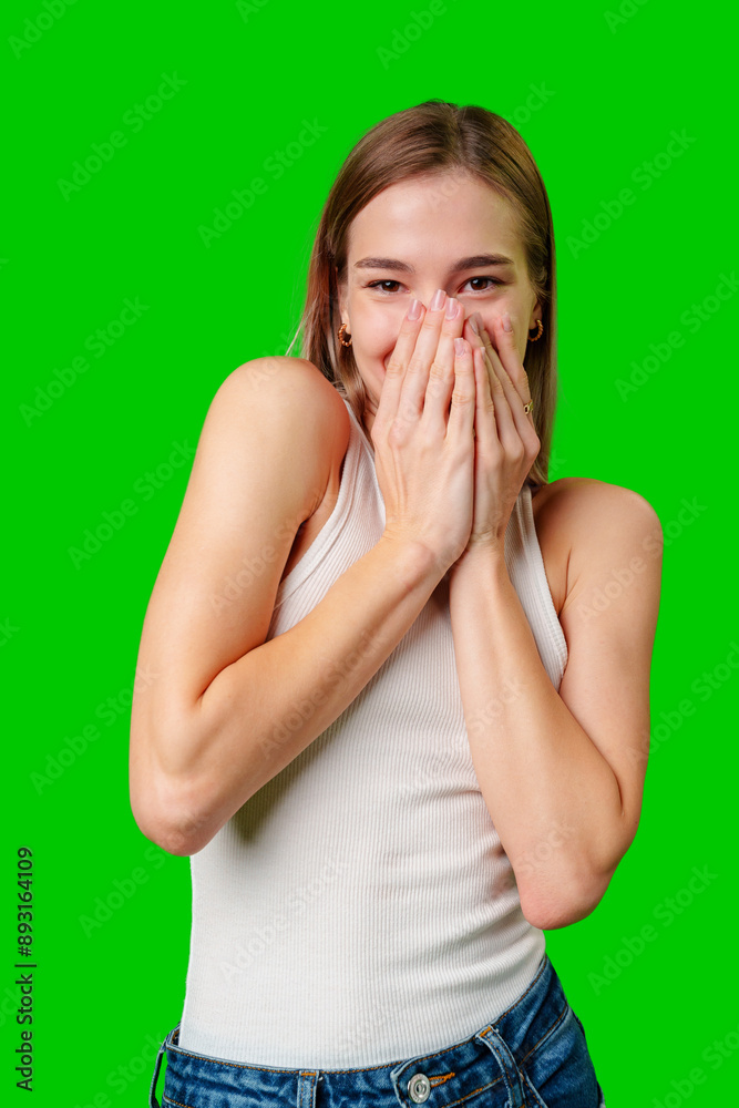 Young Woman Covering Mouth With Hands While Smiling Against Green Screen Young Woman Covering Mouth With Hands While Smiling Against Green Screen