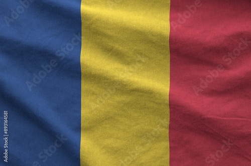 Romania flag depicted on folded wavy fabric of old cloth close up photo