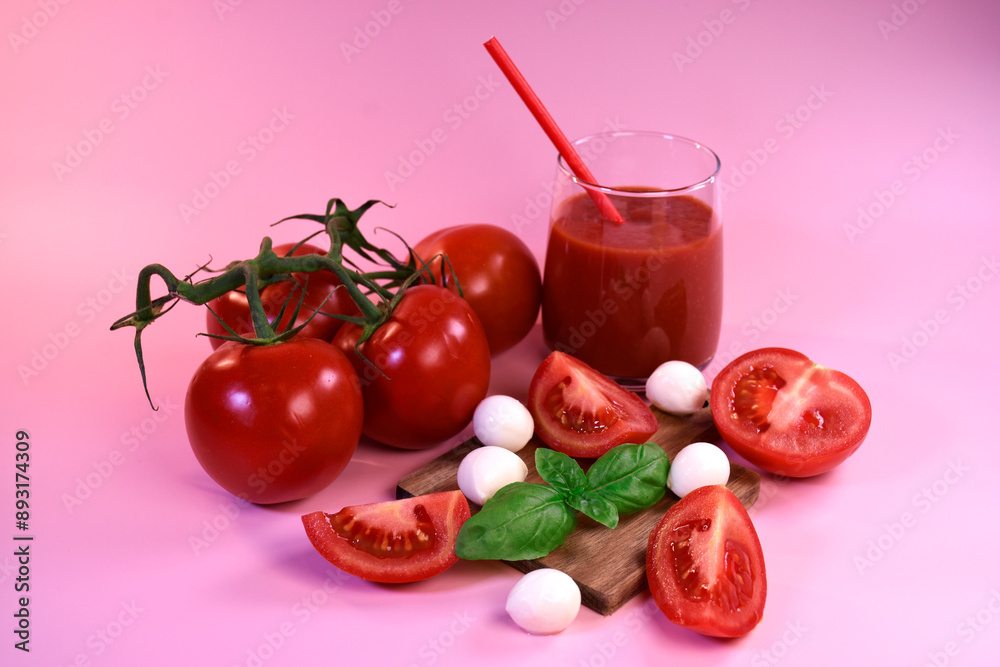 A glass of tomato juice with fresh tomatoes, mozzarella and basil on a pink background. Healthy eating A glass of tomato juice with fresh tomatoes, mozzarella and basil on a pink background. Healthy eating