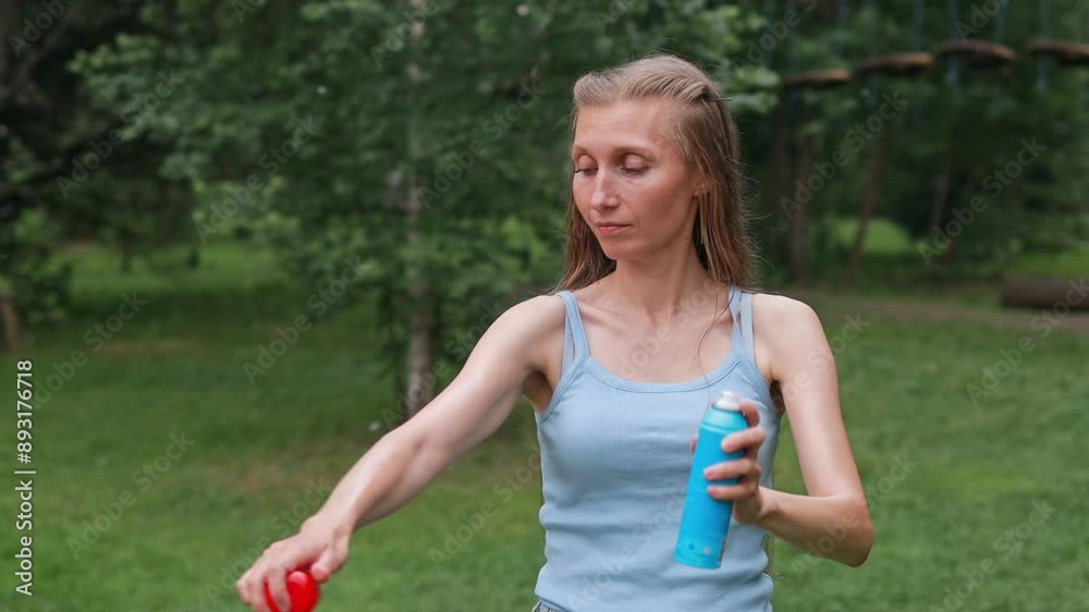 A woman holds a can of insect repellent and applies it to her skin. Mosquitoes protection. A woman holds a can of insect repellent and applies it to her skin. Mosquitoes protection.