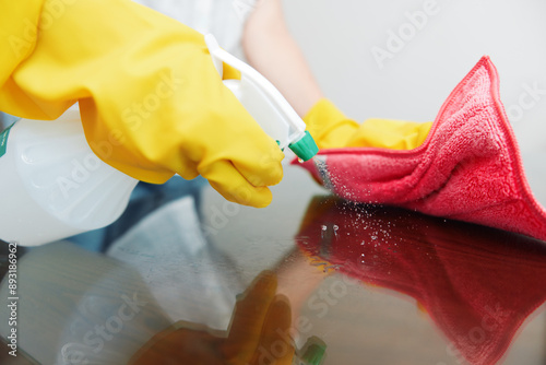 Canvastavla Woman in yellow gloves cleaning table with rag and cleaning solution bottle