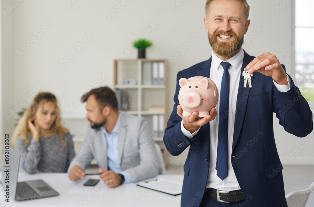 Male real estate bank agent showing piggy bank and house keys, selective focus.Buyers family couple discussing deal at meeting after successful negotiation. Family purchasing new house or apartment Male real estate bank agent showing piggy bank and house keys, selective focus.Buyers family couple discussing deal at meeting after successful negotiation. Family purchasing new house or apartment