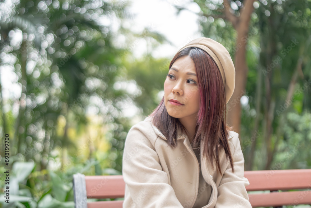 Thirty-something Hong Kong woman with reddish-brown hair sitting on a bench by a large fountain in Kowloon Park, Tsim Sha Tsui, Kowloon Island, Hong Kong, during a cold winter. Thirty-something Hong Kong woman with reddish-brown hair sitting on a bench by a large fountain in Kowloon Park, Tsim Sha Tsui, Kowloon Island, Hong Kong, during a cold winter.