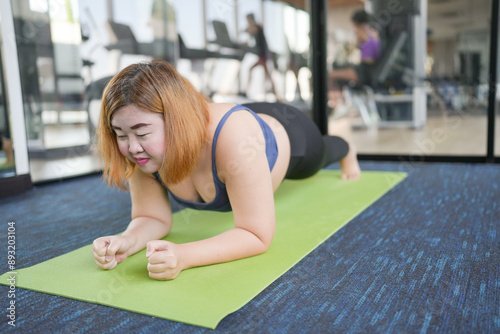 Overweight woman exercising for weight loss. plank exercise in stretching positions on mat yoga at gym Cheerful Fat woman diet healthy lifestyle