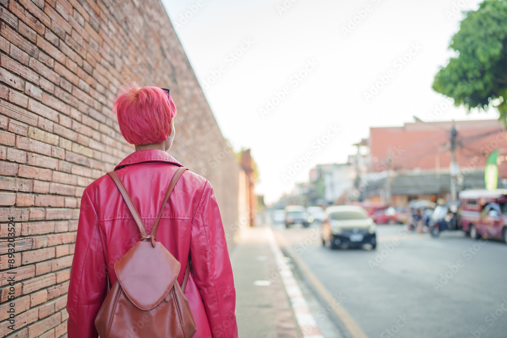 Gen z girl leather fashion with punk Asian woman tourist of local city Southeast Asia travel trendy pink hairstyle young female punk traveler walking around in town