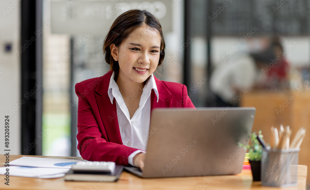 Business asian woman working on laptop, using financial calculator at modern office, analyzing business document with financial graph, market report on digital tablet, business data analysis concept Business asian woman working on laptop, using financial calculator at modern office, analyzing business document with financial graph, market report on digital tablet, business data analysis concept