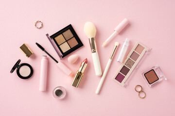 Various makeup items such as brushes, eyeshadow, lipstick, and mascara arranged on a pink background