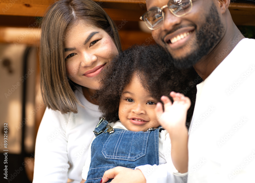 Happy multiracial family having fun relaxing together. Portrait of multiethnic father mother and little biracial daughter playing at backyard camping. Diverse ethnic dad mom leisure with afro kid