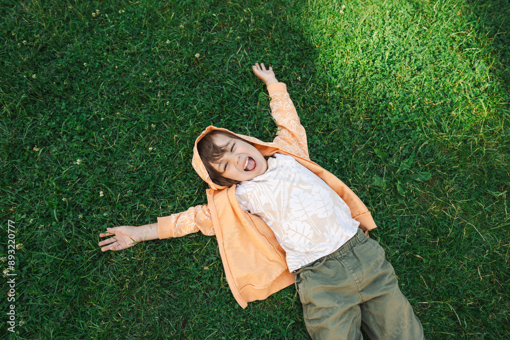 Cheerful boy lying on grass in garden Cheerful boy lying on grass in garden