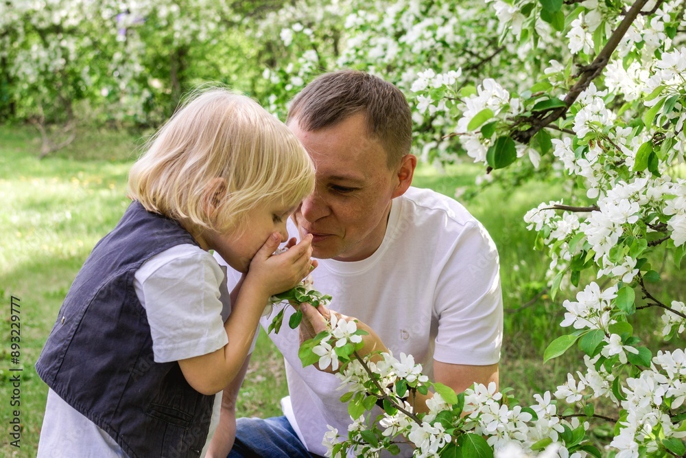 Father and Son Enjoying a Beautiful Moment in the Flower-Filled Garden Under the Warm Sunlight. Father and Son Enjoying a Beautiful Moment in the Flower-Filled Garden Under the Warm Sunlight.