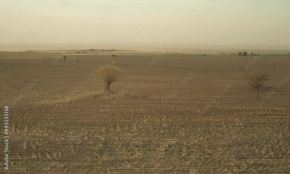 Aerial view of barren farmland suffering from drought. Dry cracked soil and sparse vegetation struggling to survive