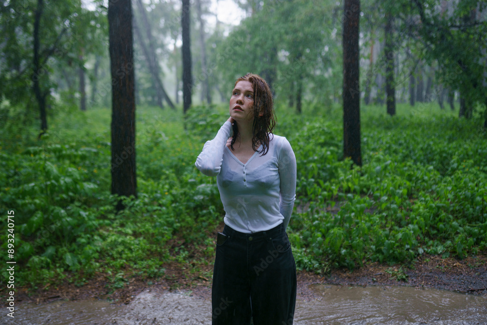 Beautiful woman with hand in hair standing in rain at forest Beautiful woman with hand in hair standing in rain at forest
