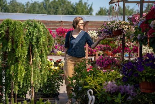 Woman buying flowering plant standing in nursery