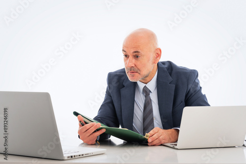 Mid aged businessman sitting at desk and using his laptop against isolated background