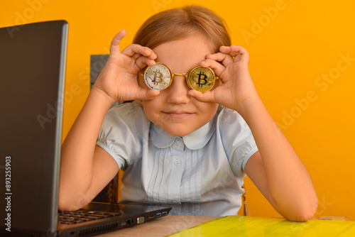 A unique child, a little girl holds bitcoin coin in front of her eyes. Young entrepreneur and financier, a child earns and accumulates cryptocurre photo