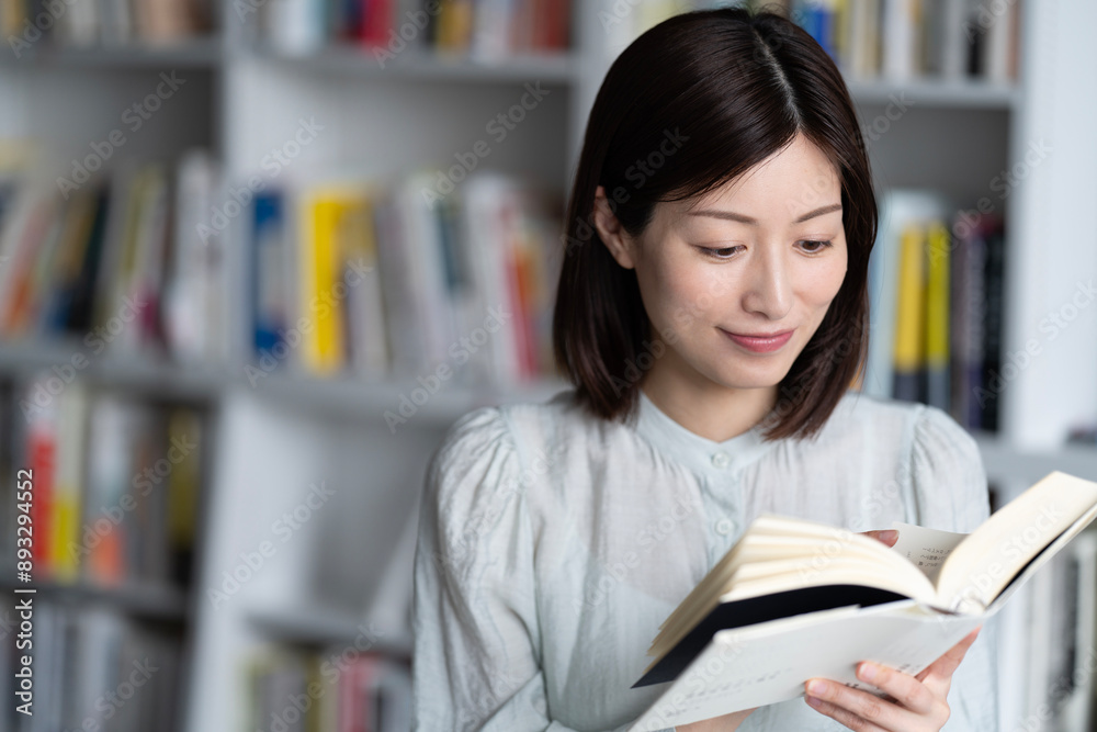 本棚の前で本を読んでいる女性 本棚の前で本を読んでいる女性