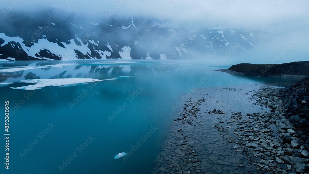 Fototapeta premium shot of the lake surrounded by mountains under the snow - capped mountain