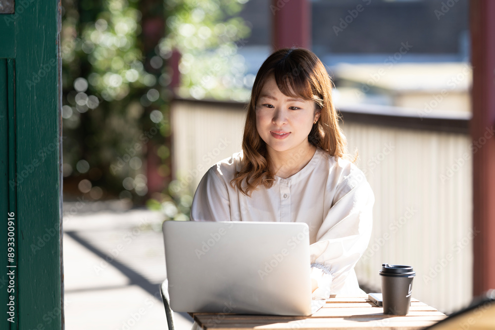 テーブルの上でパソコンを開いて作業をしている女性