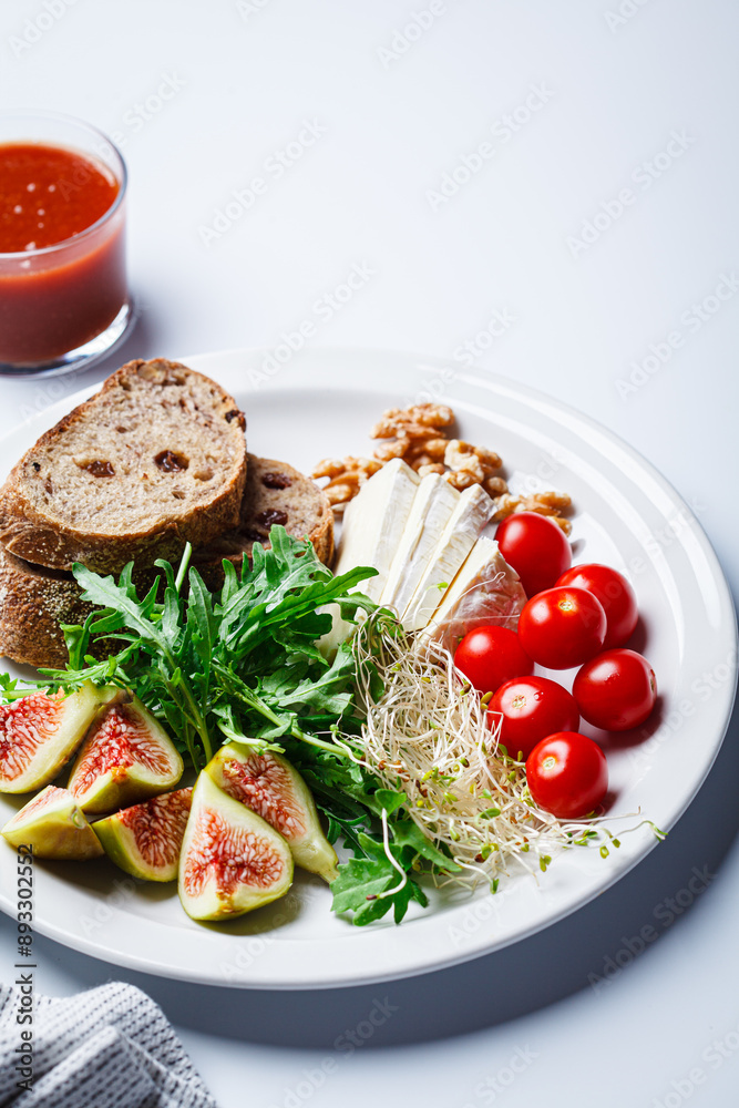 Breakfast plate with bread, tomatoes, cheese, arugula, nuts and figs on white background. Breakfast plate with bread, tomatoes, cheese, arugula, nuts and figs on white background.