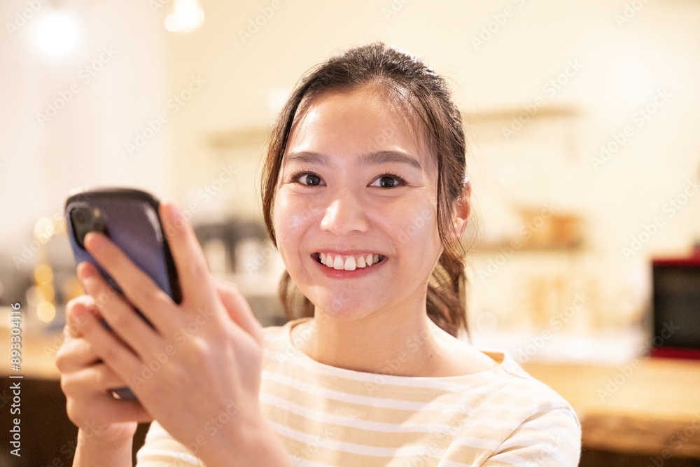 カフェの店内でスマホを持っている笑顔の女性 カフェの店内でスマホを持っている笑顔の女性