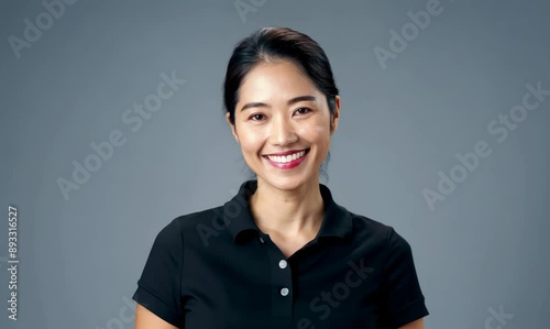 Smiling asian woman in black polo shirt on grey background