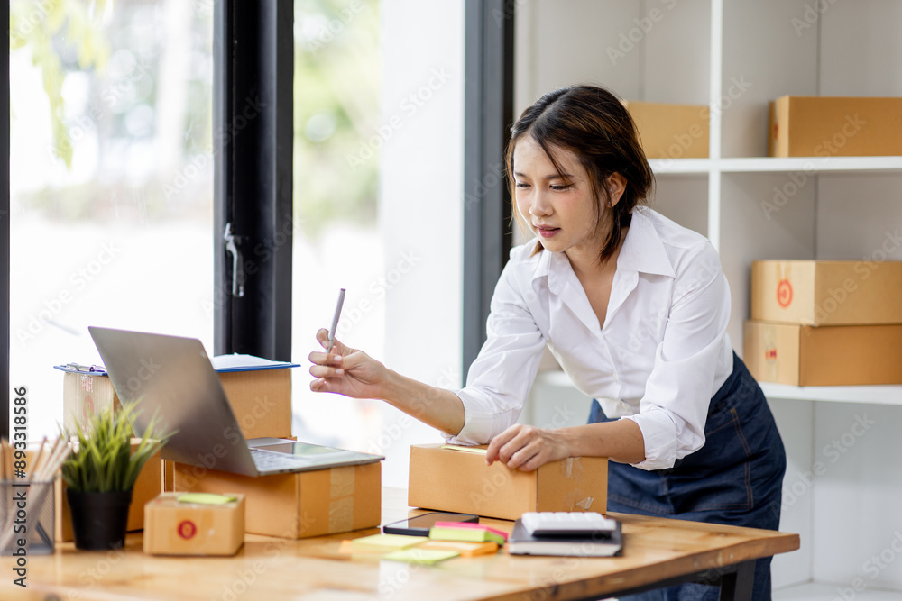 SME concept. Young asian female ecommerce business owner prepares package box for customer and delivery check balance. SME small business entrepreneur SME or freelance SME concept. Young asian female ecommerce business owner prepares package box for customer and delivery check balance. SME small business entrepreneur SME or freelance