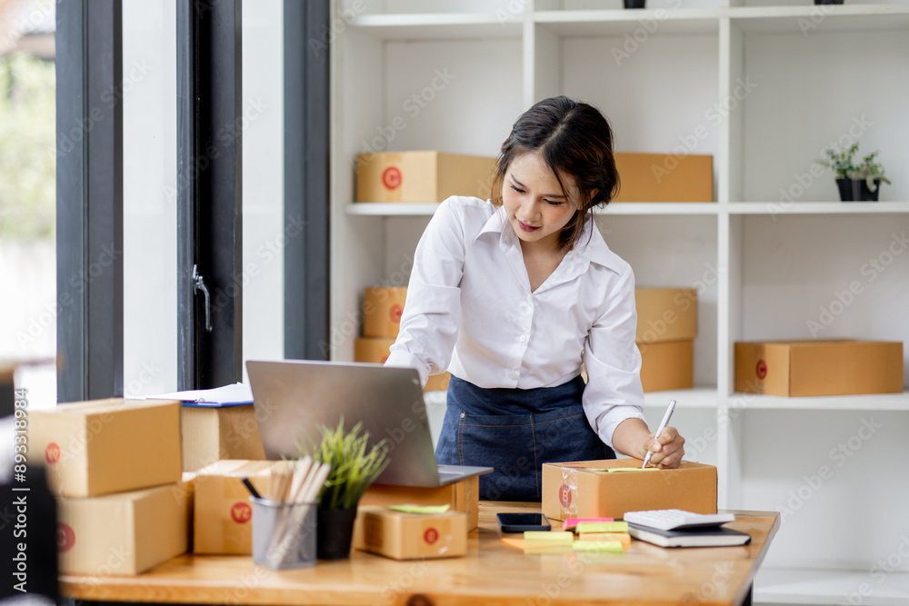 SME concept. Young asian female ecommerce business owner prepares package box for customer and delivery check balance. SME small business entrepreneur SME or freelance SME concept. Young asian female ecommerce business owner prepares package box for customer and delivery check balance. SME small business entrepreneur SME or freelance
