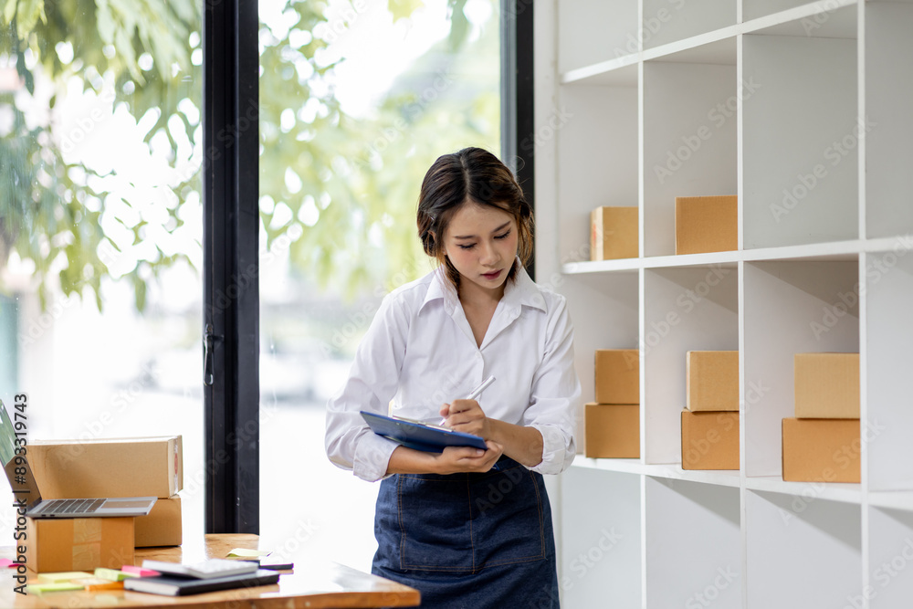 SME concept. Young asian female ecommerce business owner prepares package box for customer and delivery check balance. SME small business entrepreneur SME or freelance SME concept. Young asian female ecommerce business owner prepares package box for customer and delivery check balance. SME small business entrepreneur SME or freelance
