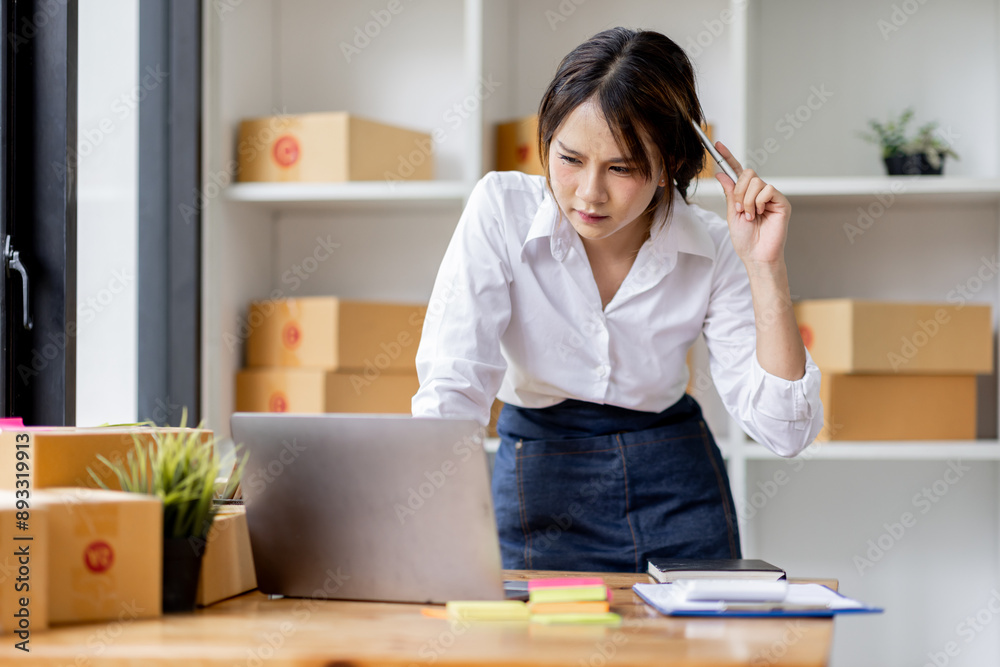 SME concept. Young asian female ecommerce business owner prepares package box for customer and delivery check balance. SME small business entrepreneur SME or freelance SME concept. Young asian female ecommerce business owner prepares package box for customer and delivery check balance. SME small business entrepreneur SME or freelance