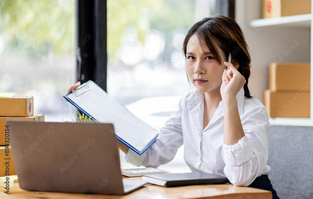 SME concept. Young asian female ecommerce business owner prepares package box for customer and delivery check balance. SME small business entrepreneur SME or freelance SME concept. Young asian female ecommerce business owner prepares package box for customer and delivery check balance. SME small business entrepreneur SME or freelance