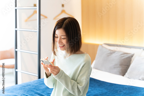 ホテルの部屋でスマホを触っている女性 photo