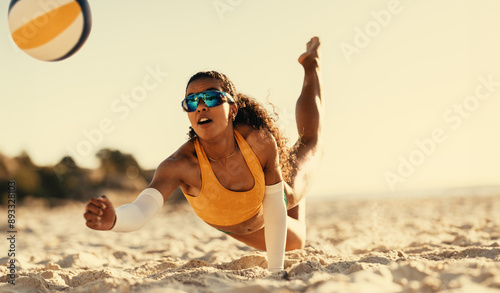 Young brazilian athlete spikes ball on beach volleyball court