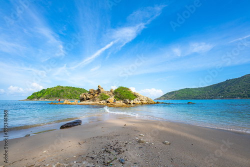 Blue sky over a small island surrounded by blue sea. White beach dotted with coconut trees. Yanui Beach, a viewpoint next to Promthep Cape and windmills, is a small beach with a split sea. photo