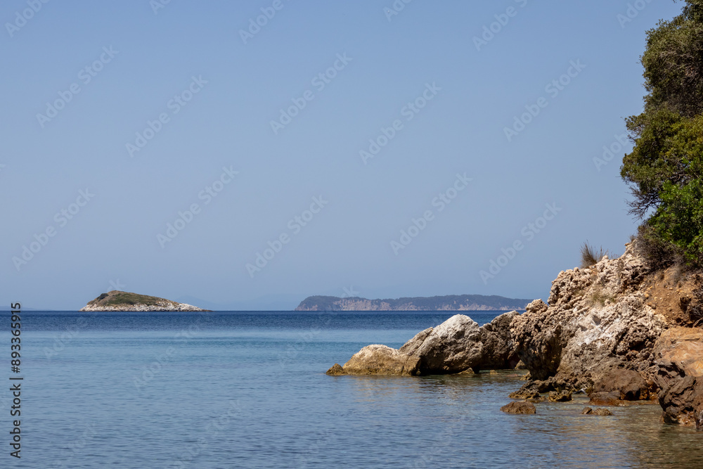 Fototapeta premium Panoramic view of a serene coastal landscape featuring calm blue waters and distant hills under a clear sky. Peaceful and tranquil scene perfect for relaxation and travel concepts.